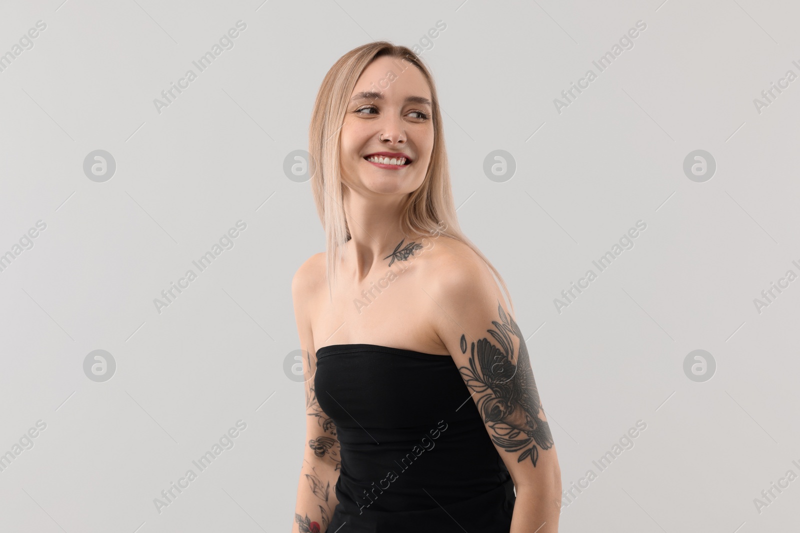 Photo of Portrait of beautiful tattooed woman on light background