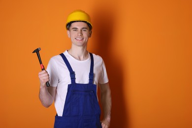 Photo of Professional repairman holding hammer on orange background. Space for text