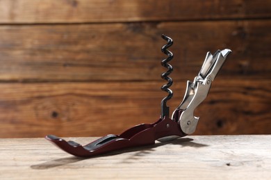 Photo of One corkscrew (sommelier knife) on wooden table, closeup