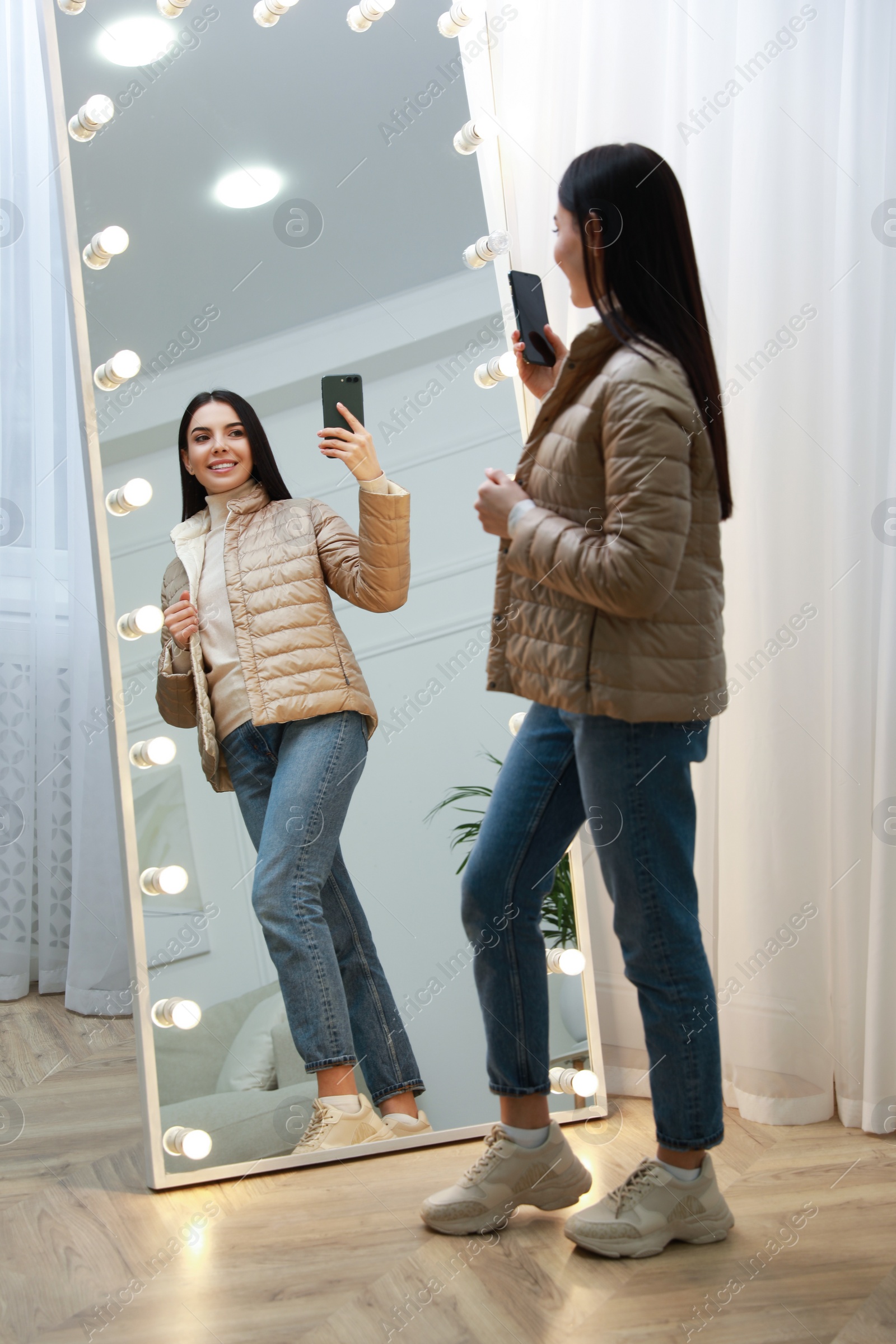 Photo of Young woman taking mirror selfie in stylish outfit at home. Morning routine