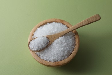 Photo of Organic white salt in bowl and spoon on olive background, above view