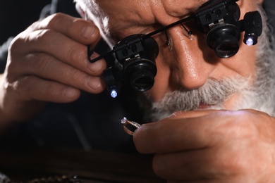 Male jeweler evaluating diamond ring in workshop, closeup view