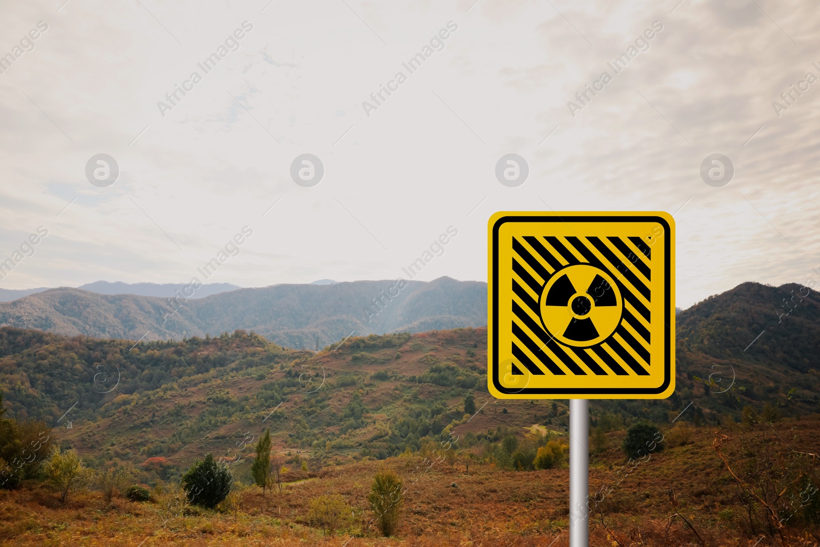 Image of Radioactive pollution. Yellow warning sign with hazard symbol in rural area