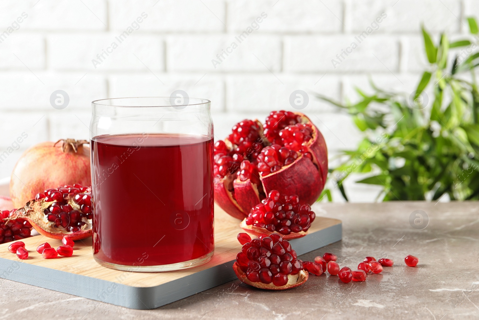 Photo of Composition with glass of fresh pomegranate juice on table. Space for text