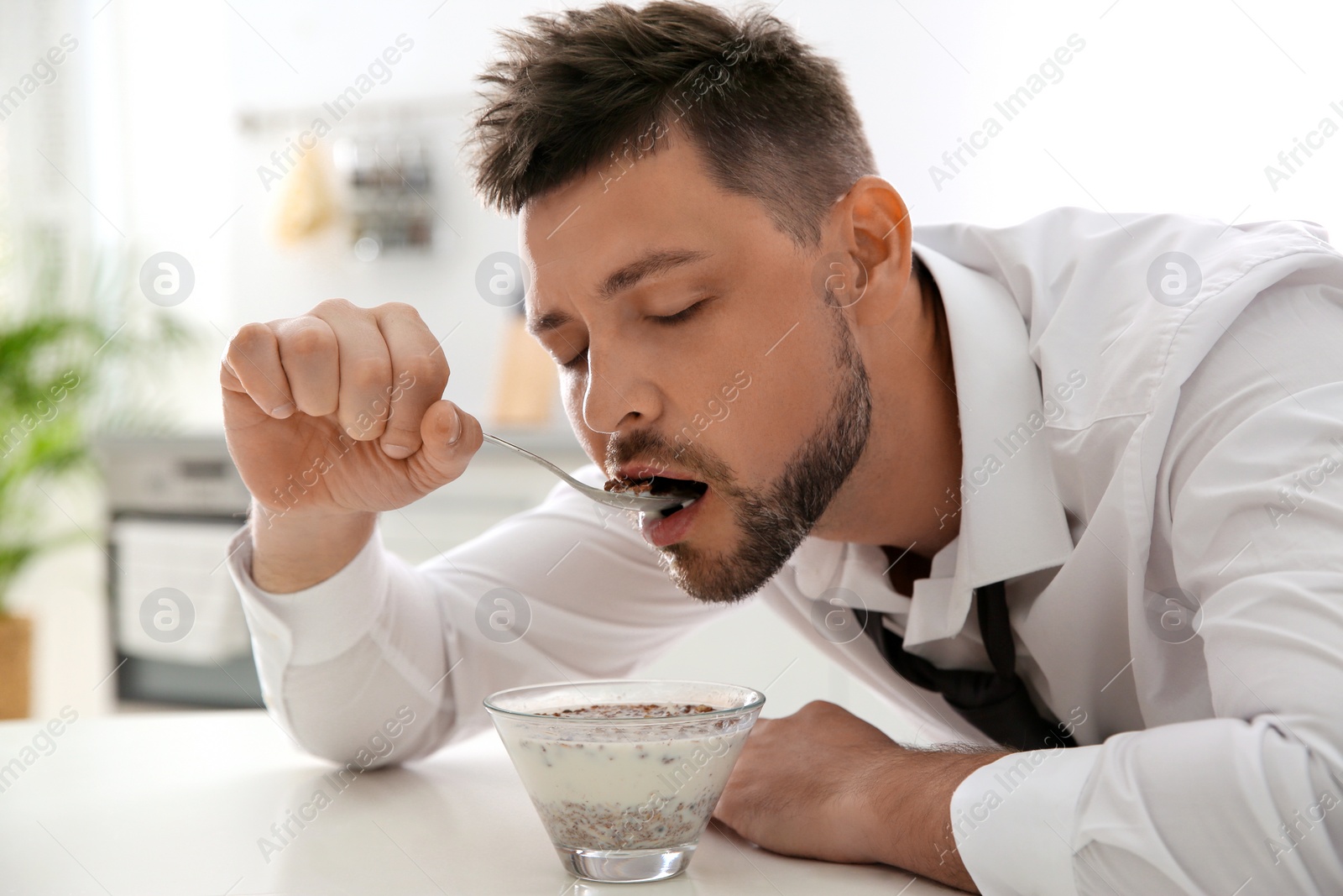 Photo of Sleepy man eating breakfast at home in morning