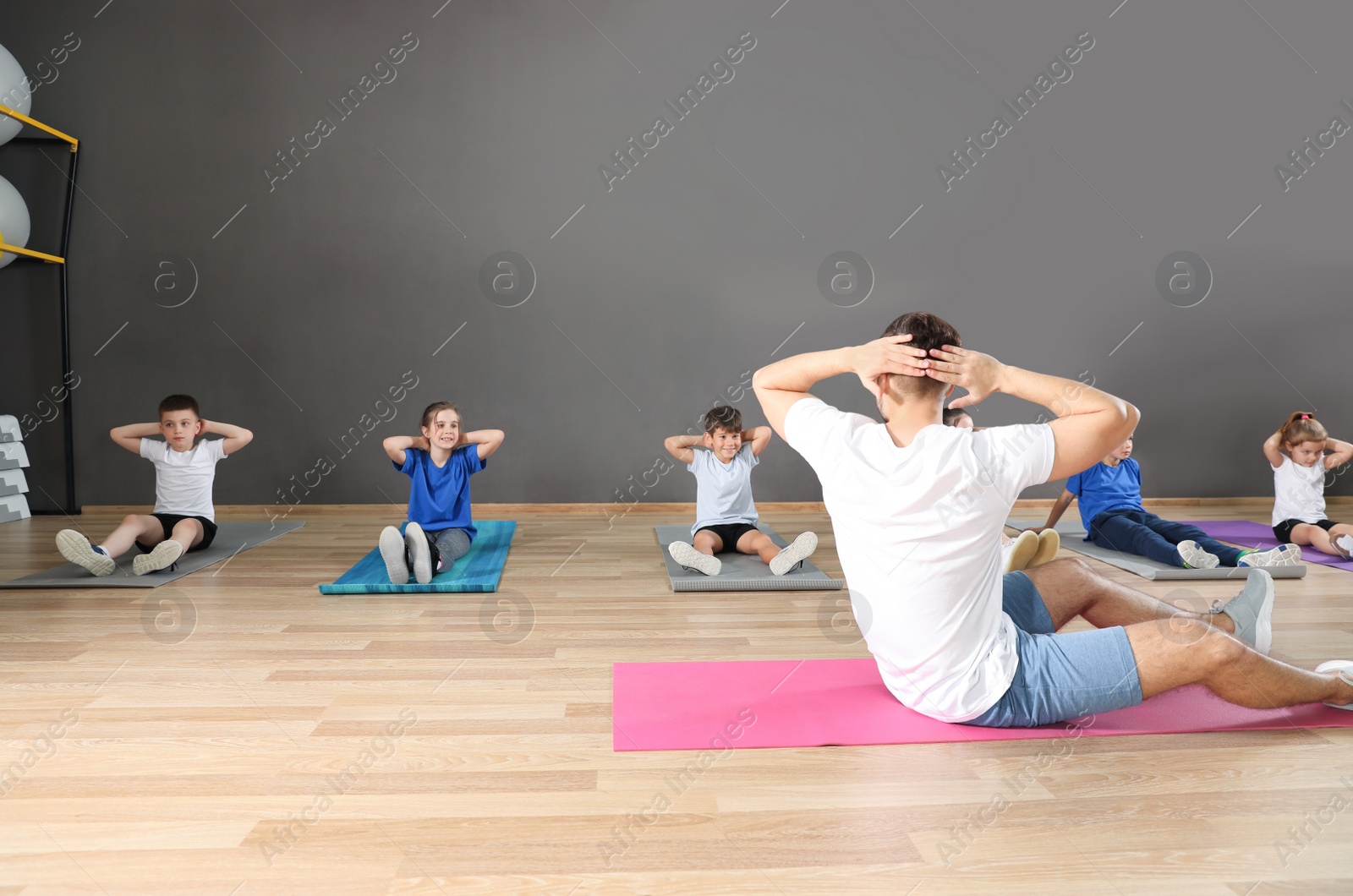 Photo of Cute little children and trainer doing physical exercise in school gym. Healthy lifestyle