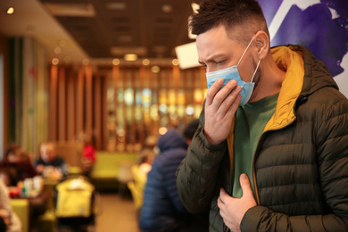 Photo of Man with disposable mask in cafe. Virus protection