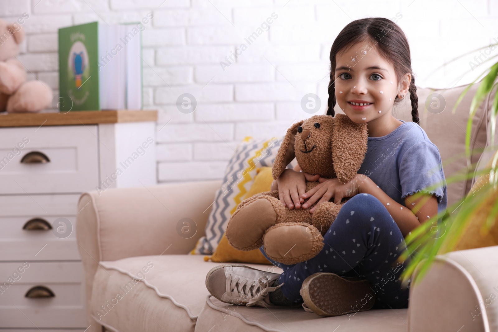 Photo of Little girl with chickenpox playing at home. Space for text