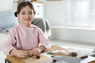 Little girl working with natural materials at table indoors, space for text. Creative hobby