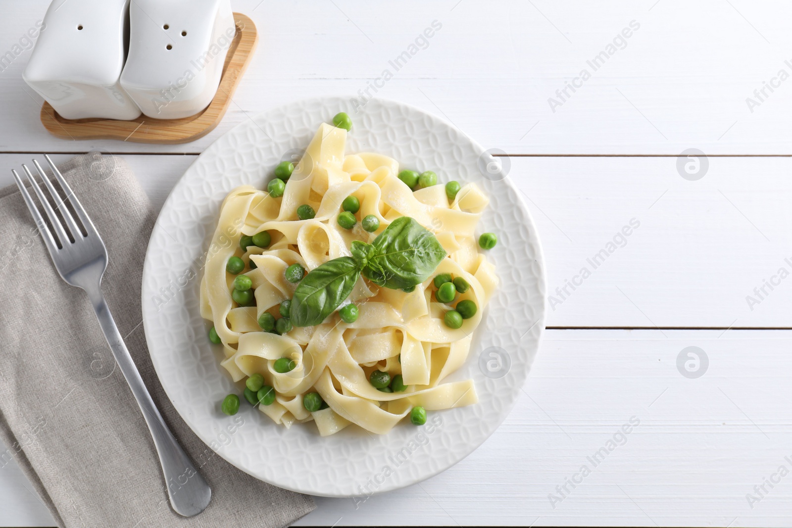 Photo of Delicious pasta with green peas served on white wooden table, flat lay. Space for text