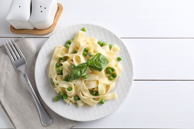 Photo of Delicious pasta with green peas served on white wooden table, flat lay. Space for text