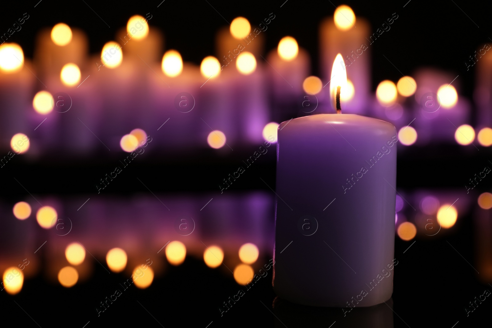 Image of Burning violet candle in darkness, space for text. Funeral attributes