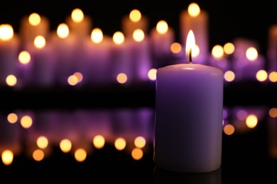 Burning violet candle in darkness, space for text. Funeral attributes