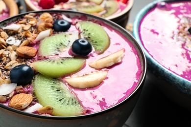Photo of Delicious acai smoothie with granola and fruits in dessert bowl, closeup