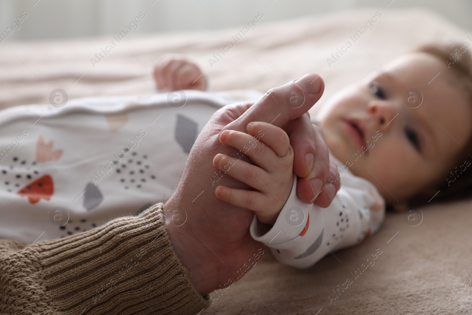 Photo of Father holding hands with his daughter on bed, closeup