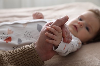 Photo of Father holding hands with his daughter on bed, closeup