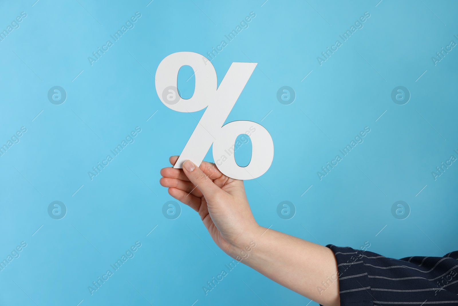 Photo of Woman holding percent sign on light blue background, closeup