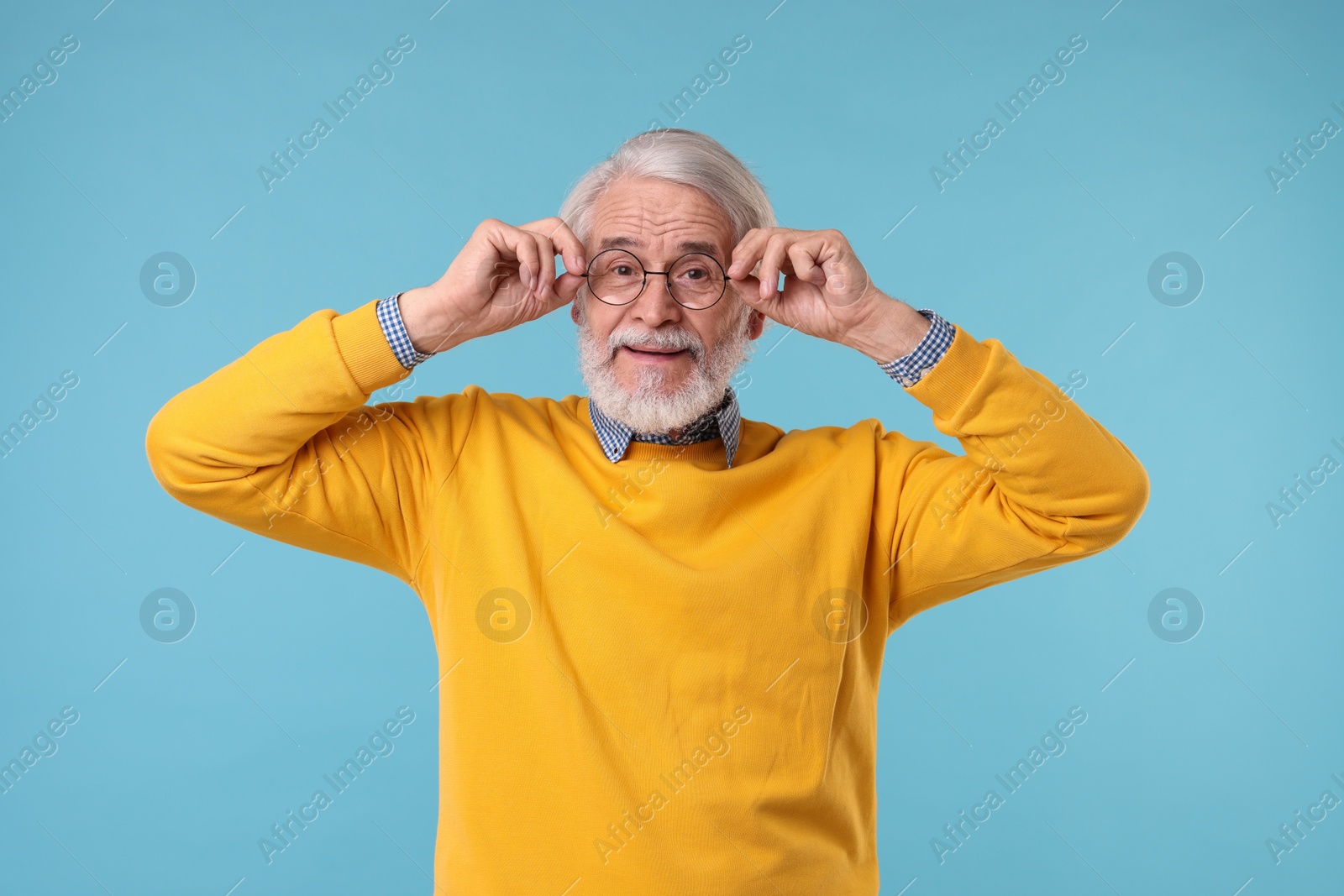 Photo of Portrait of stylish grandpa with glasses on light blue background