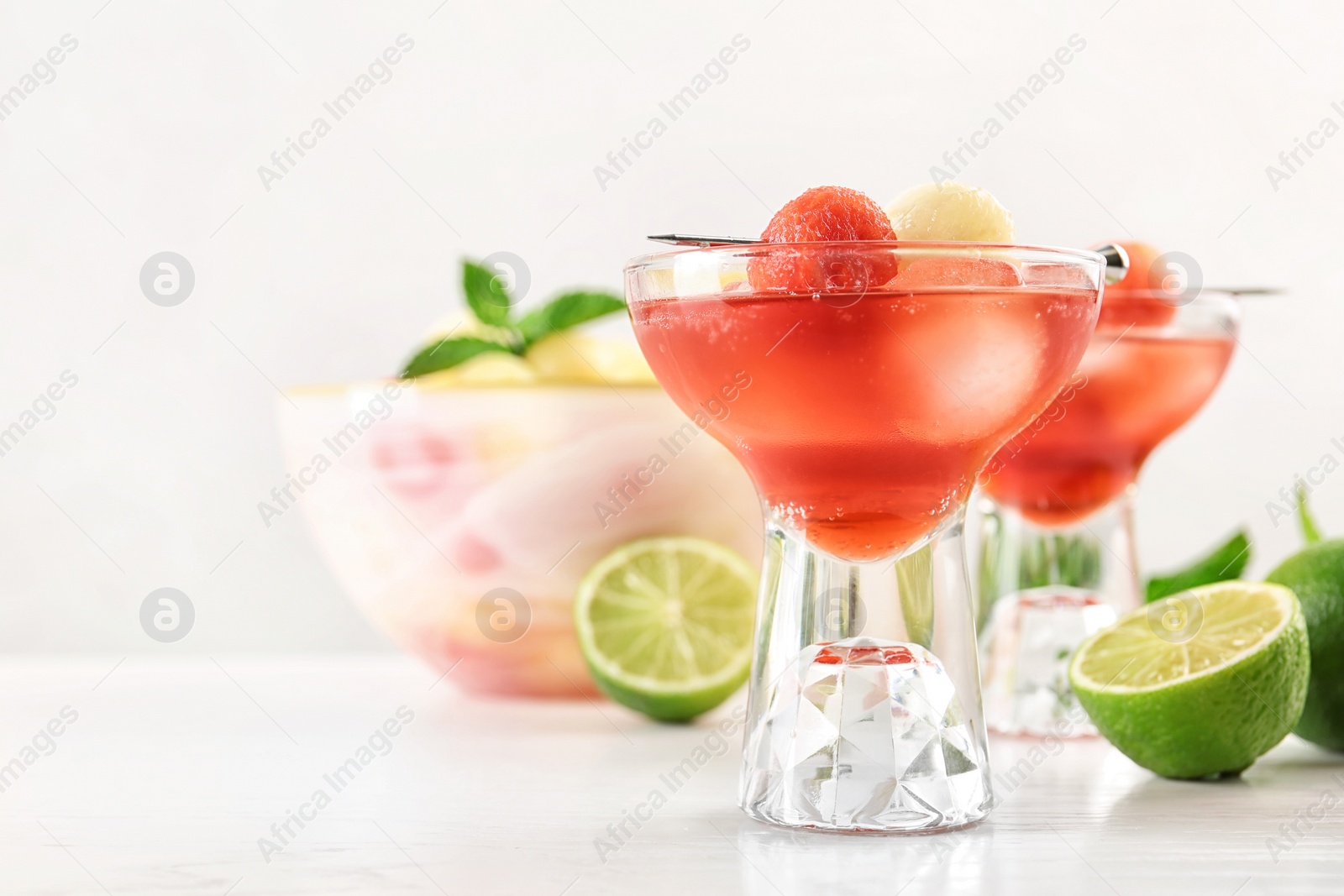 Photo of Glass of melon and watermelon ball cocktail on white wooden table. Space for text