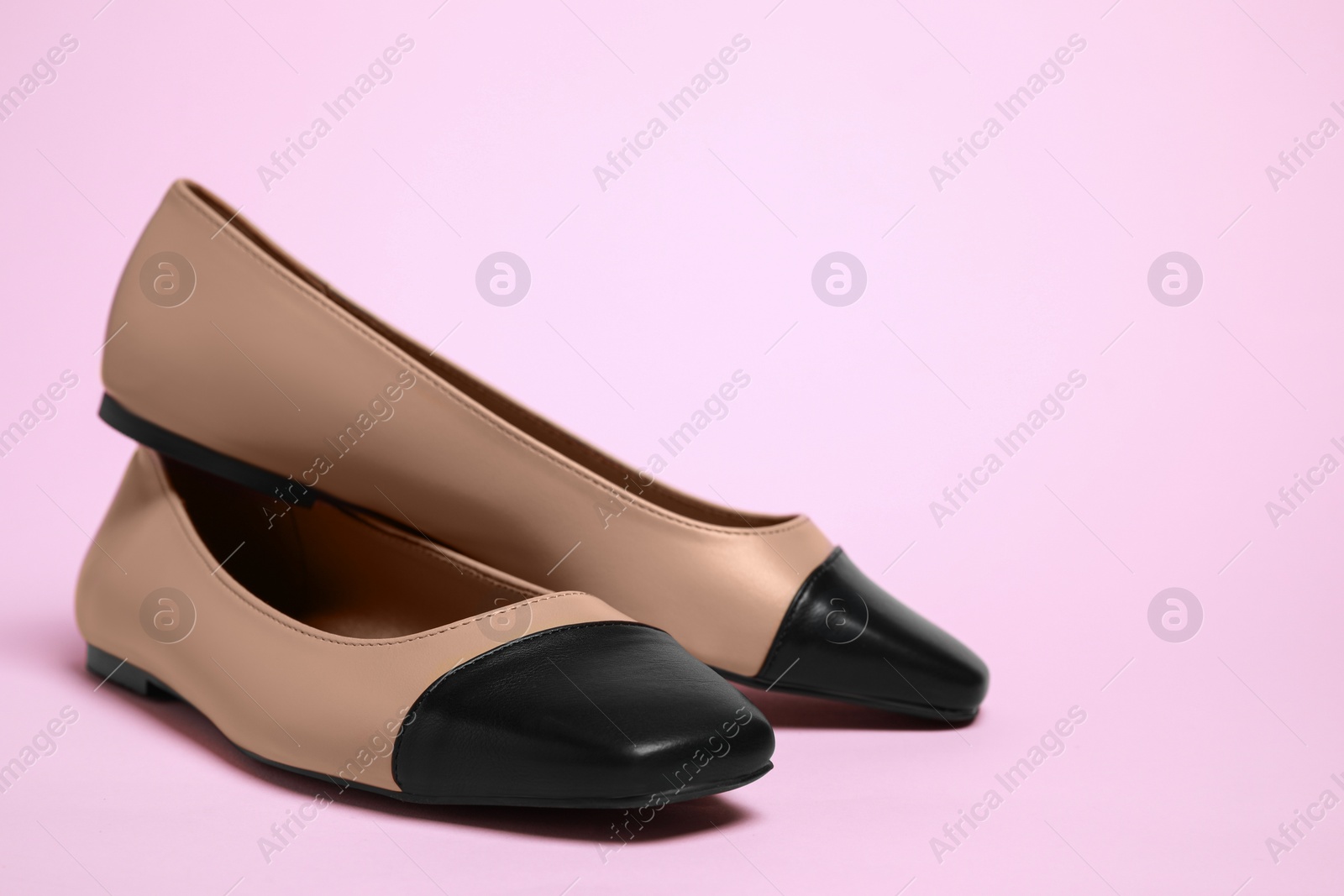 Photo of Pair of new stylish square toe ballet flats on pale pink background