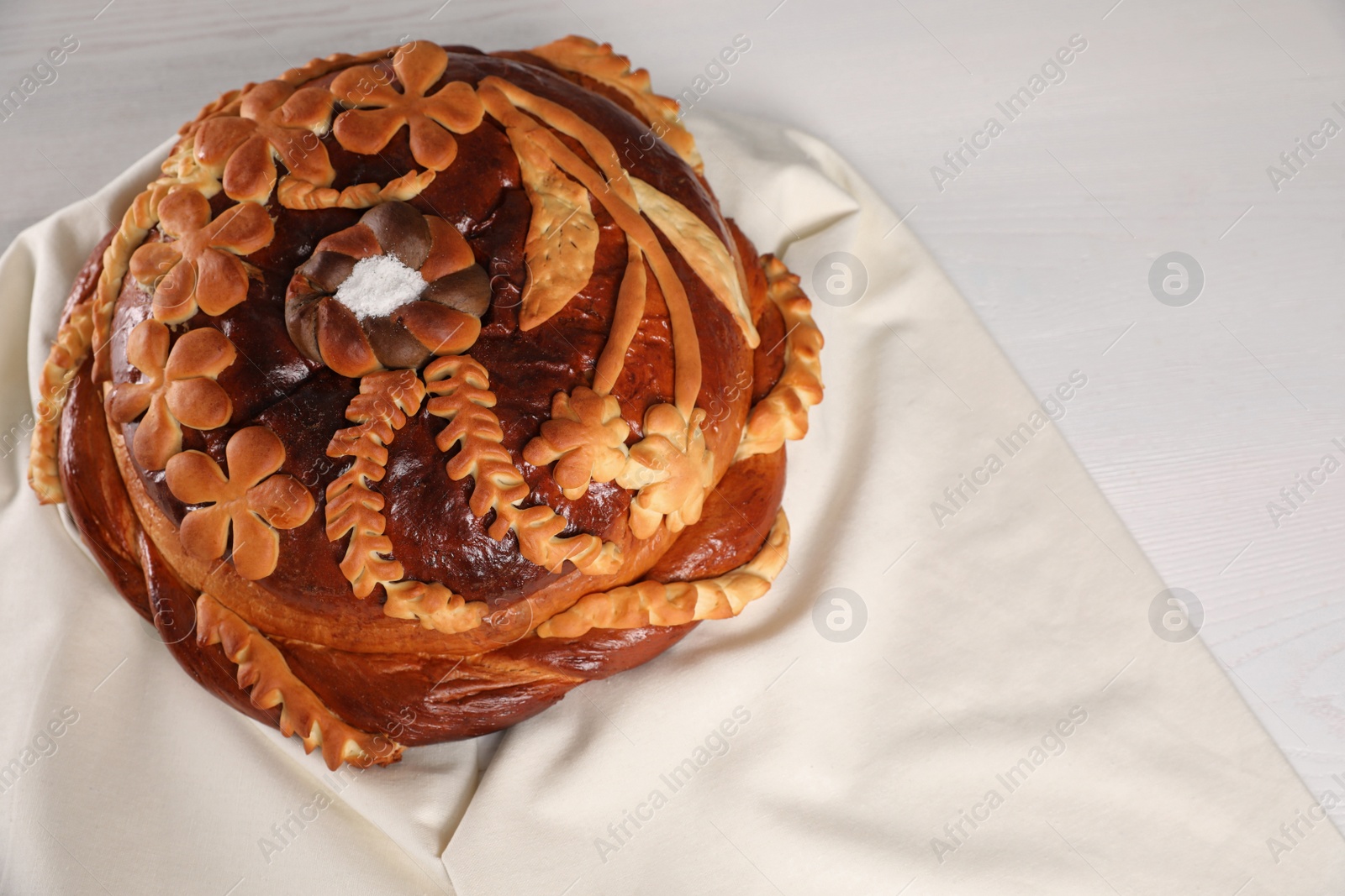 Photo of Korovai on white table, above view. Ukrainian bread and salt welcoming tradition