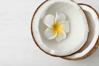Photo of Halves of coconut and flower on white wooden background