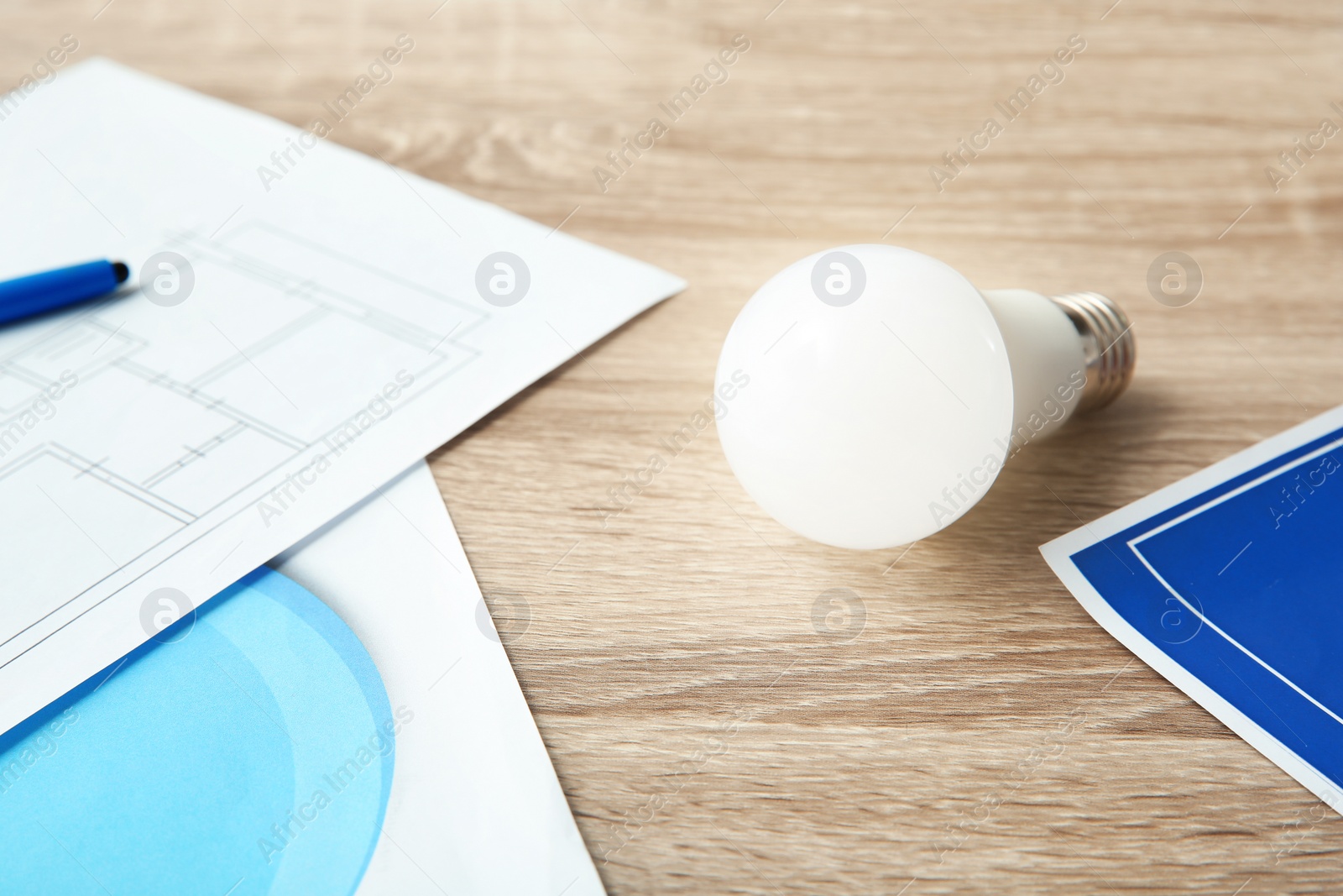 Photo of Lamp bulb and house plan on wooden table