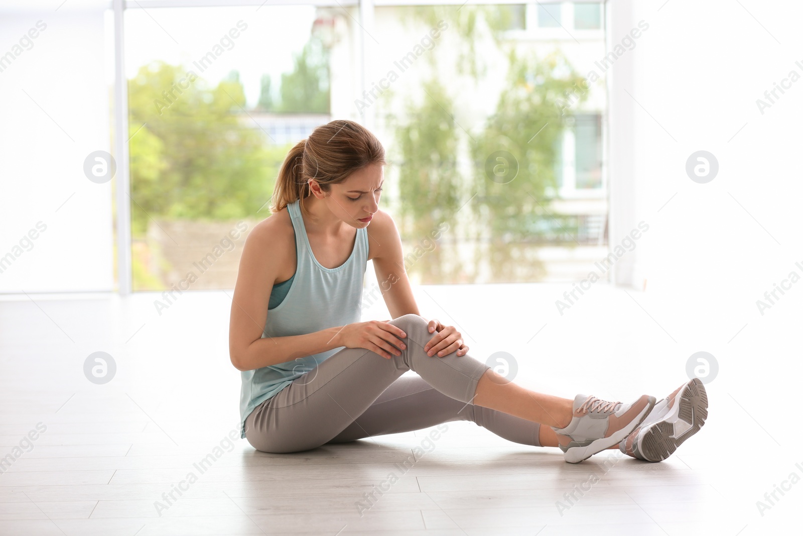 Photo of Woman in sportswear suffering from knee pain at gym