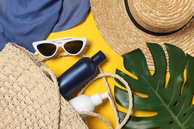 Flat lay composition with wicker bag, green leaf and other beach accessories on yellow background