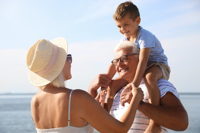 Photo of Cute little boy with grandparents spending time together near sea
