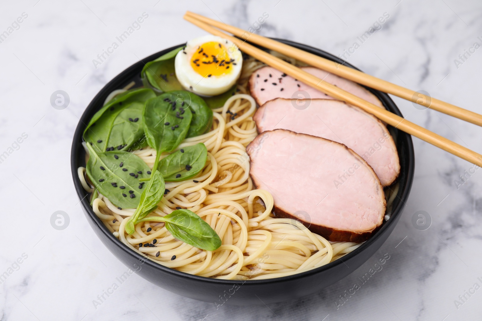 Photo of Delicious ramen with meat on white marble table, closeup. Noodle soup