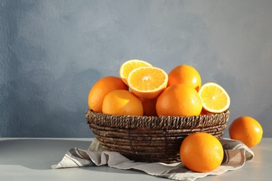 Fresh juicy oranges in wicker basket on table. Space for text