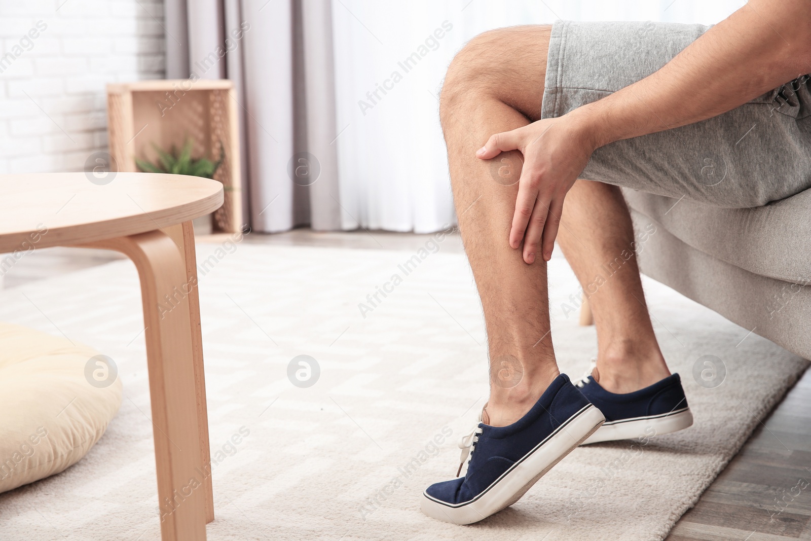 Photo of Man suffering from leg pain at home, closeup. Space for text