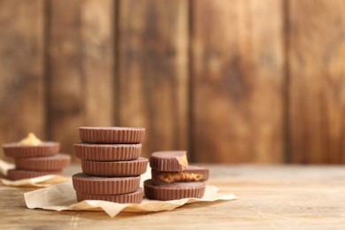 Photo of Delicious peanut butter cups on wooden table, space for text