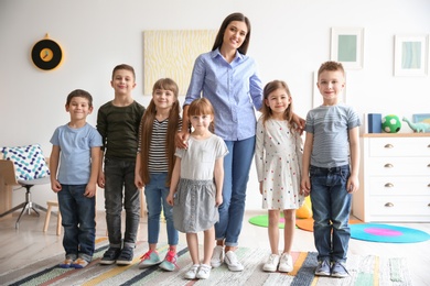 Photo of Cute little children with teacher in classroom at school