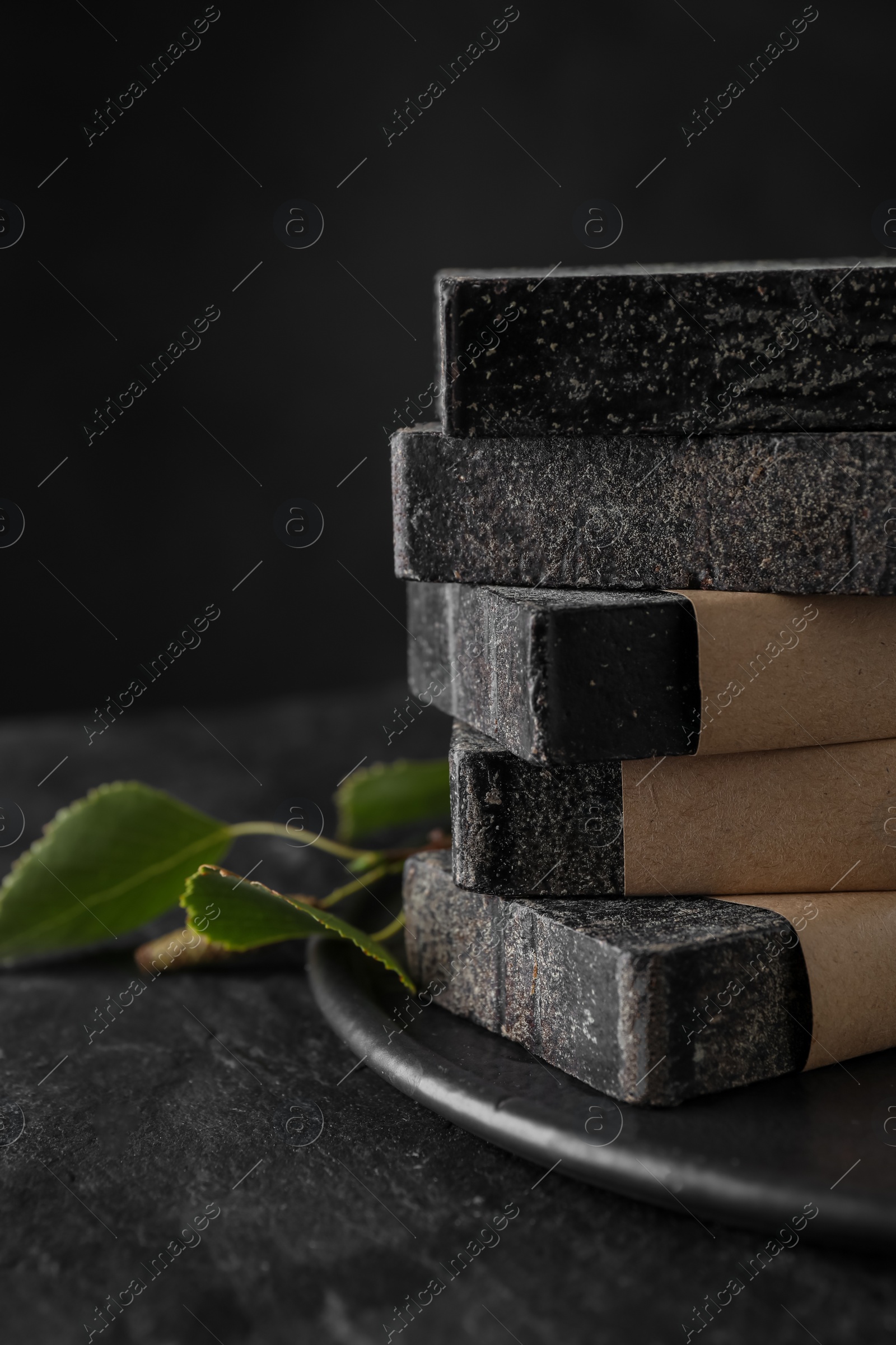 Photo of Stack of natural tar soap on black table, closeup