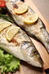 Photo of Delicious baked fish, lettuce and lemon on table, closeup