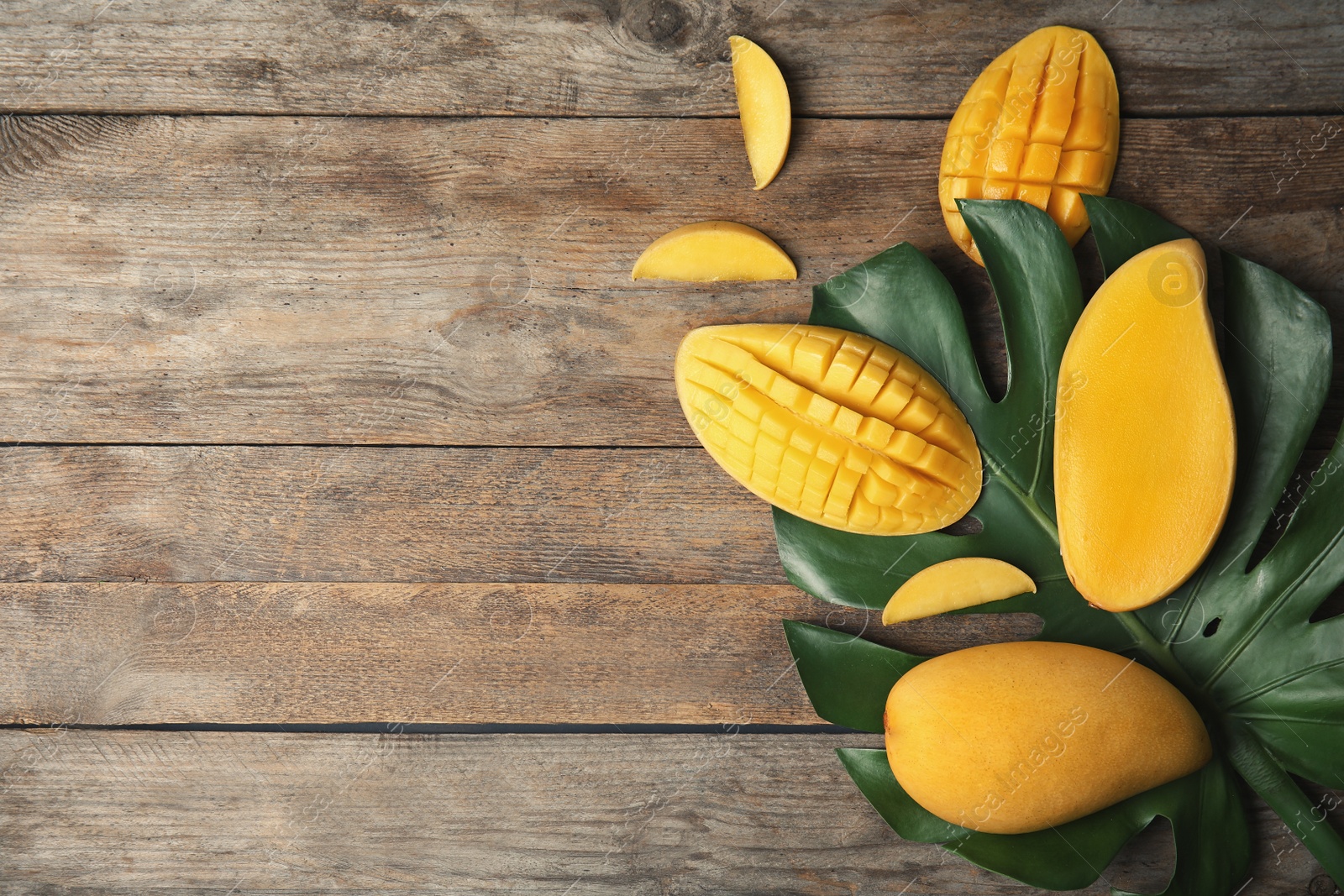 Photo of Flat lay composition with mango and tropical leaf on wooden background. Space for text