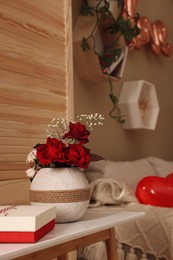 Photo of Vase with beautiful flowers and gift box on wooden table in room. Happy Valentine's Day