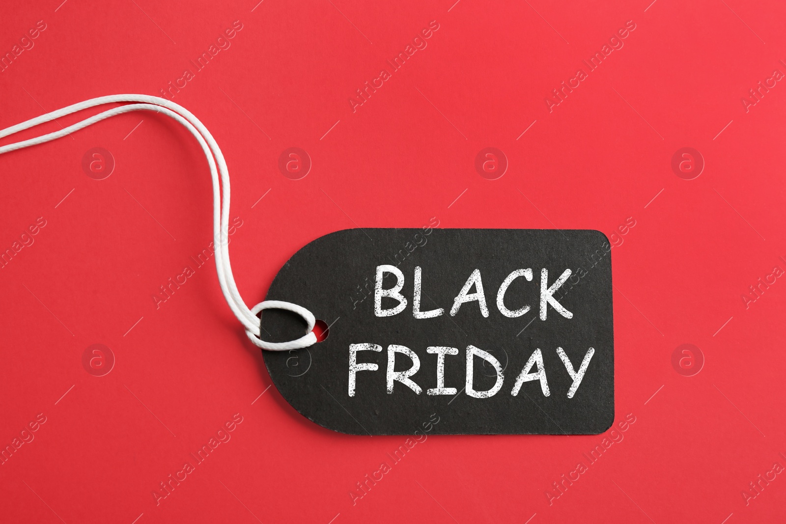 Photo of Tag with words BLACK FRIDAY on red background, top view
