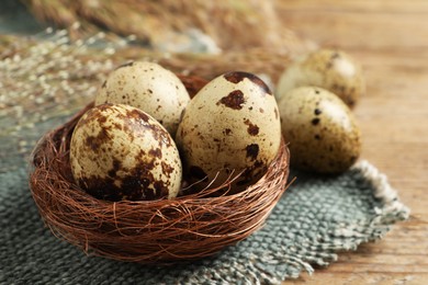 Photo of Nest with quail eggs on wooden table, closeup