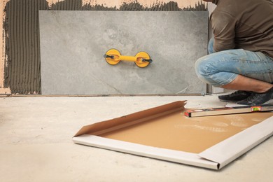 Professional worker installing tile on wall indoors, closeup