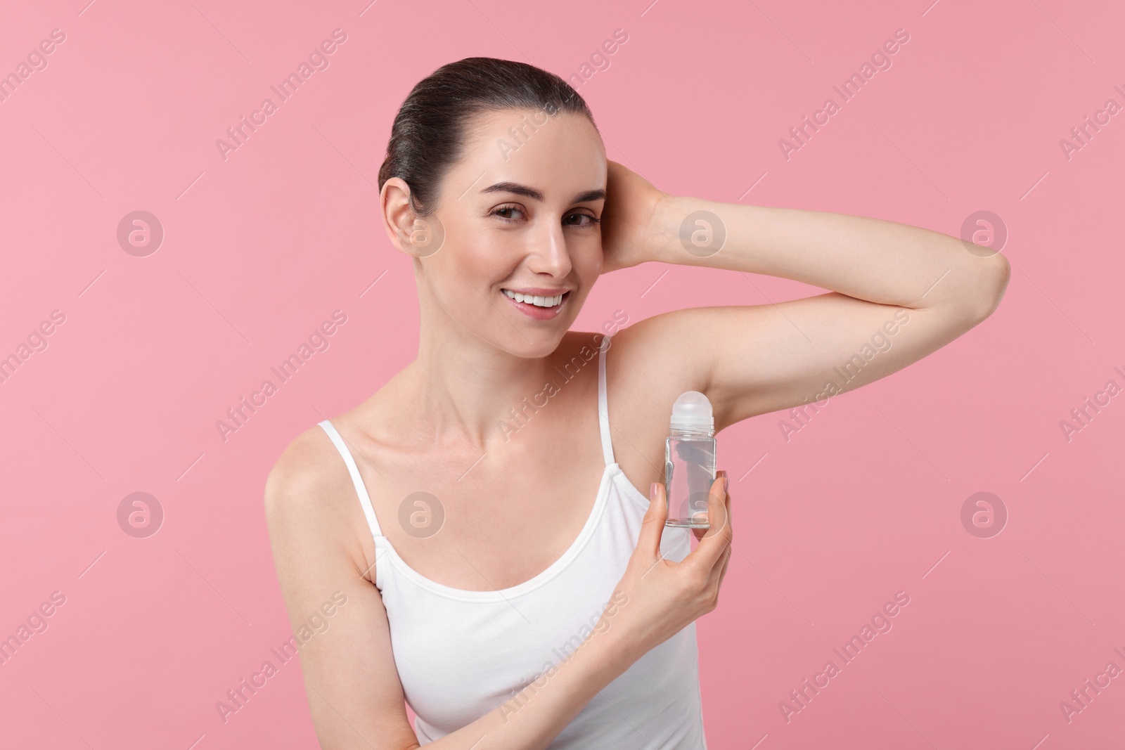 Photo of Beautiful woman applying deodorant on pink background