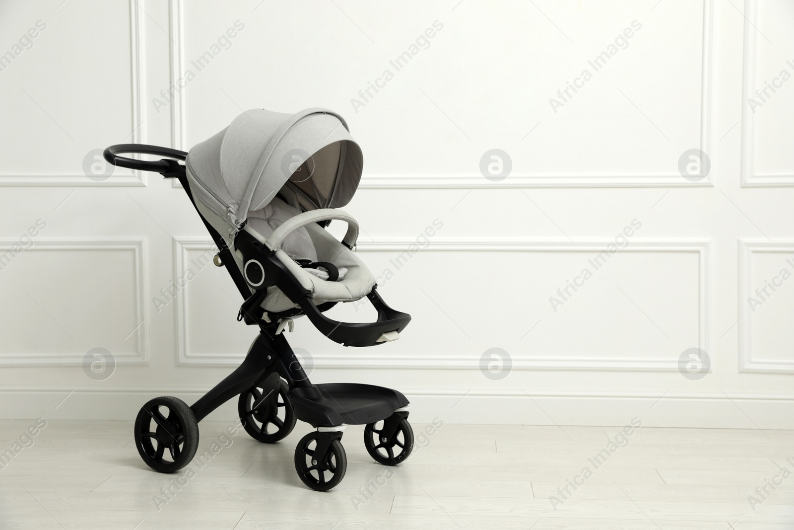 Photo of Baby carriage. Modern pram near white wall, space for text