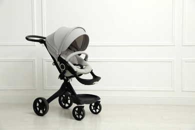 Photo of Baby carriage. Modern pram near white wall, space for text