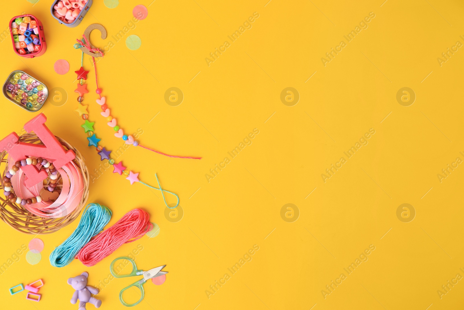 Photo of Kid`s handmade jewelry kit. Colorful beads, bracelets and different supplies on orange background, flat lay. Space for text