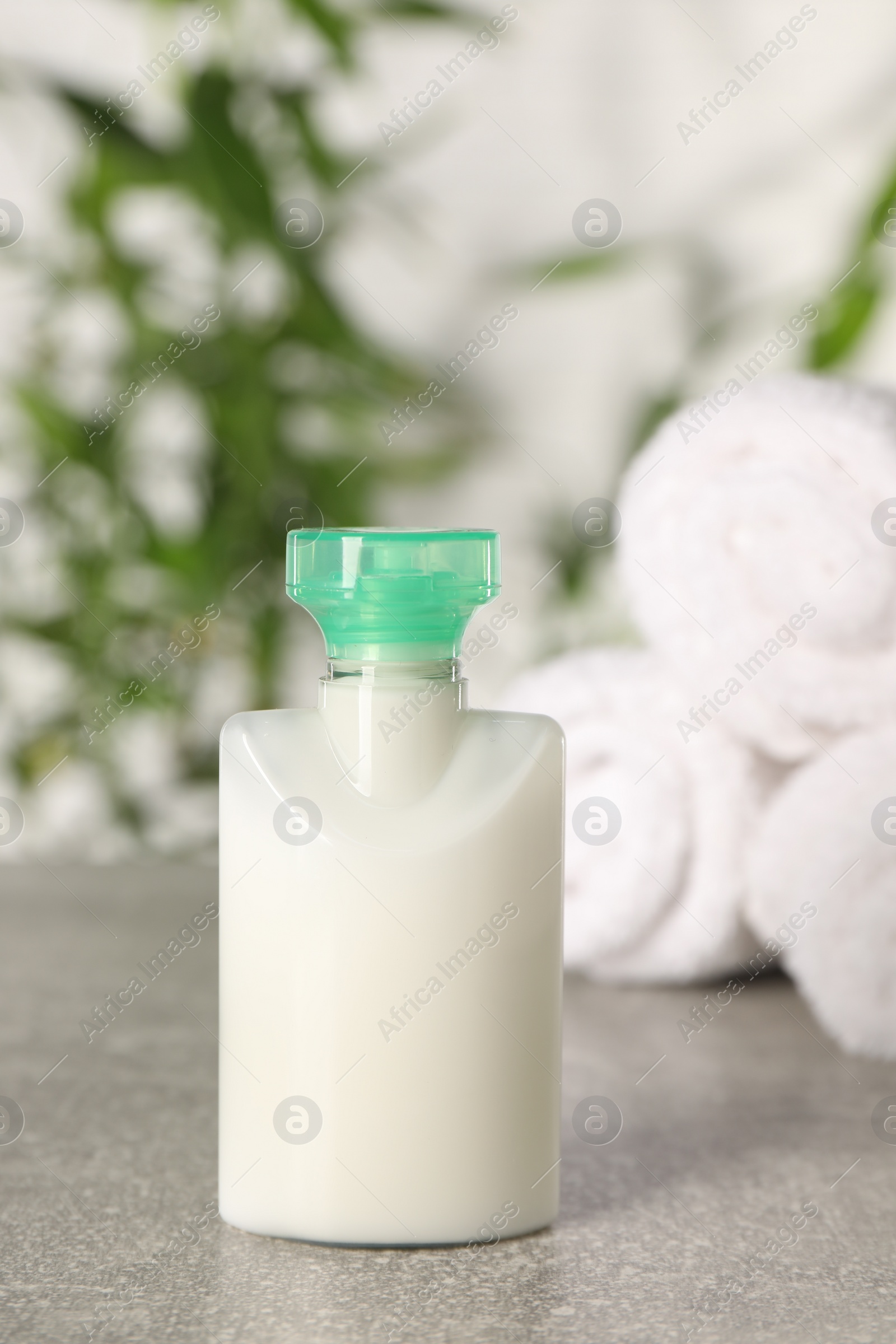 Photo of Mini bottle of cosmetic product on light grey table against blurred background