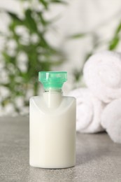 Mini bottle of cosmetic product on light grey table against blurred background