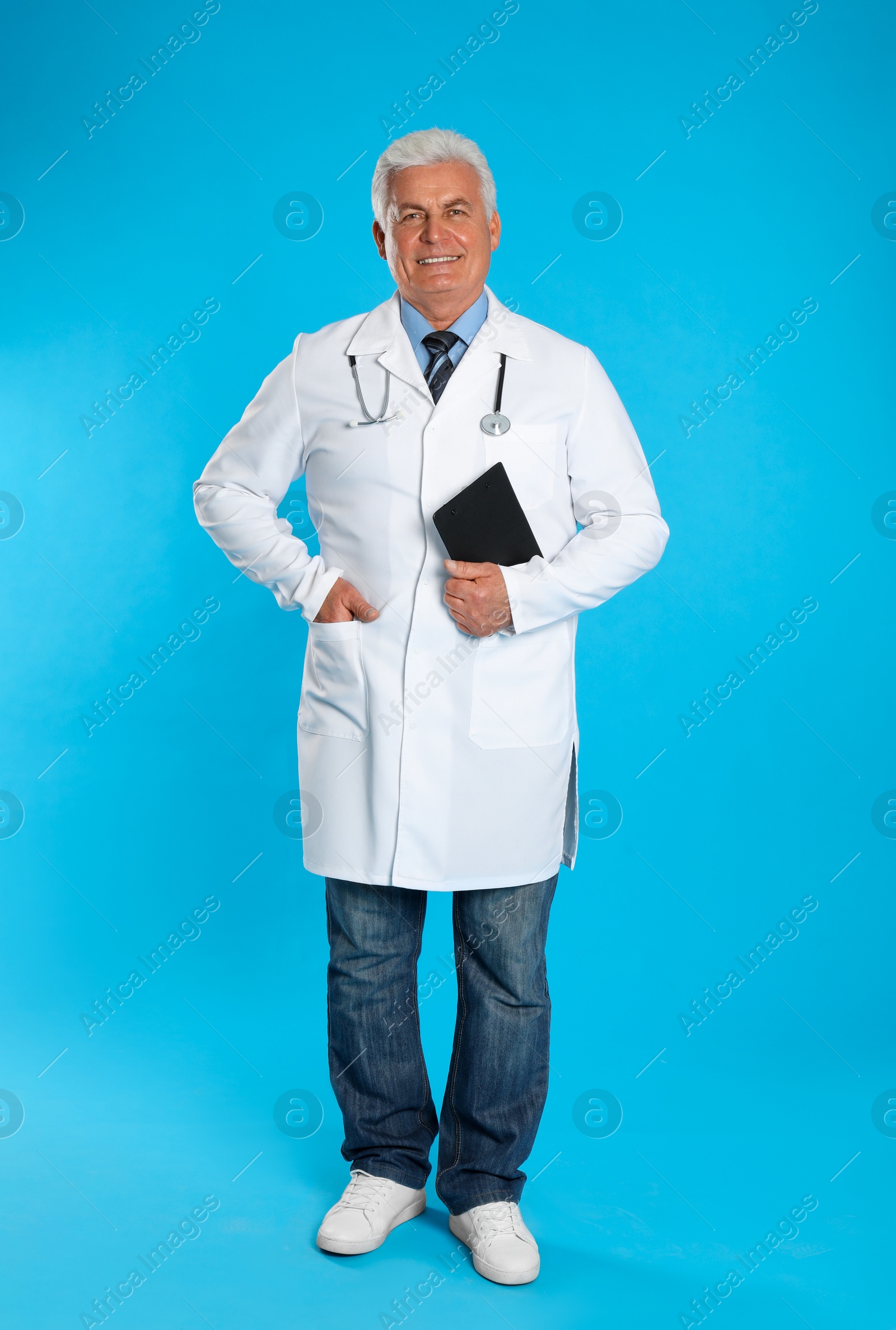 Photo of Senior doctor with clipboard on light blue background