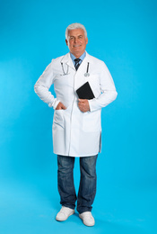 Senior doctor with clipboard on light blue background